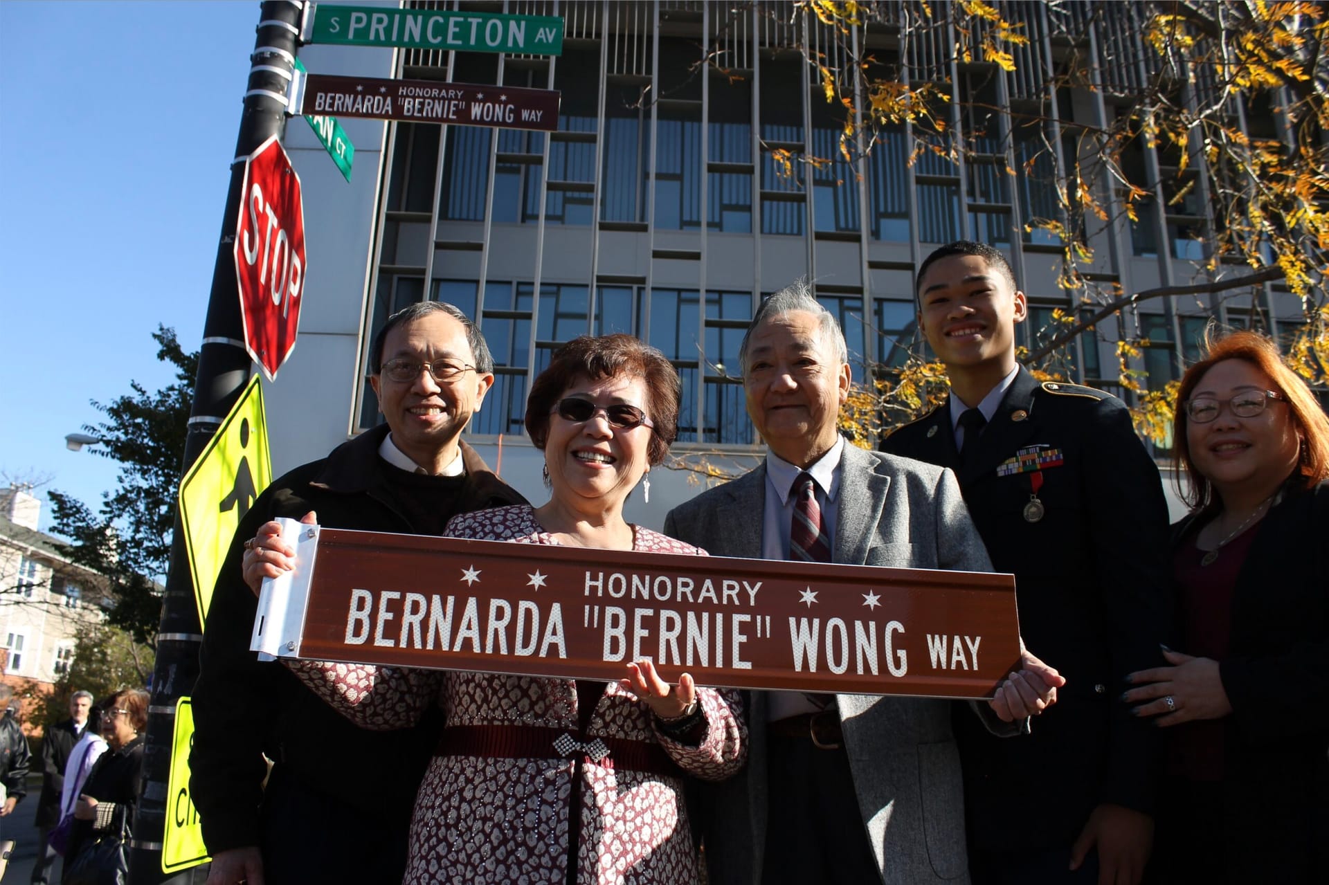 Bernie Wong holding the honorary street sign that reads "Bernarda 'Bernie' Wong Way"